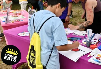 up close photo of boy painting at a table during summer eats kickoff party