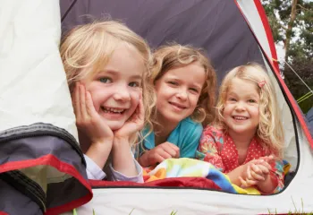 three young girls sitting together in a tent