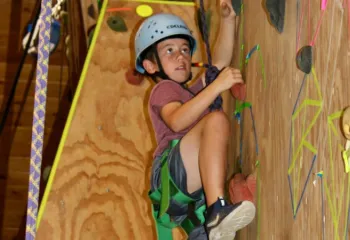 photo of boy on indoor climbing wall