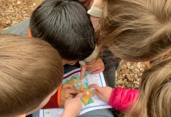 image of young kids huddled around a map
