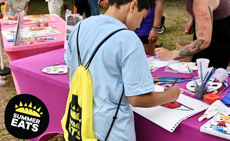 up close photo of boy painting at a table during summer eats kickoff party