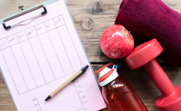 image of workout plan, apple, dumbbell, water bottle, and towel