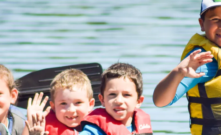 image of young kids waving from a canoe