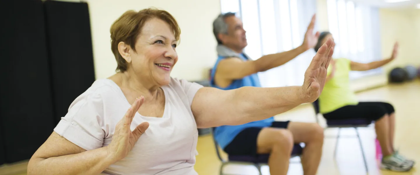 senior citizens smiling and exercising while seated