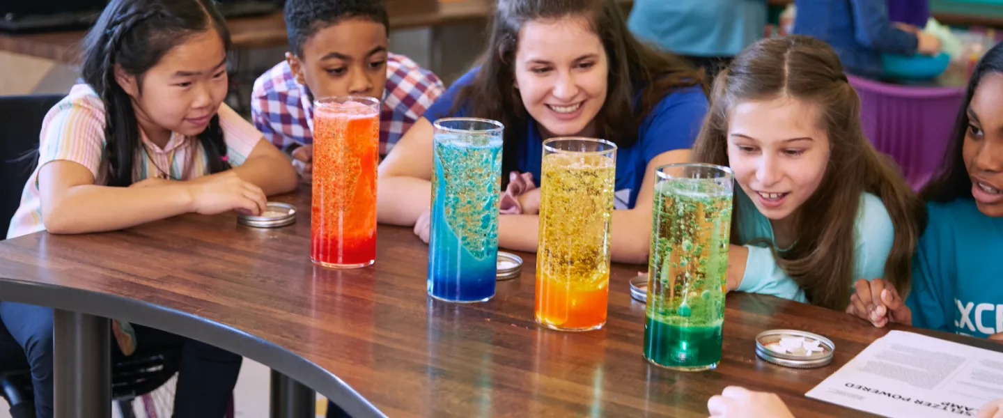 Teacher and students observe colorful science experiment