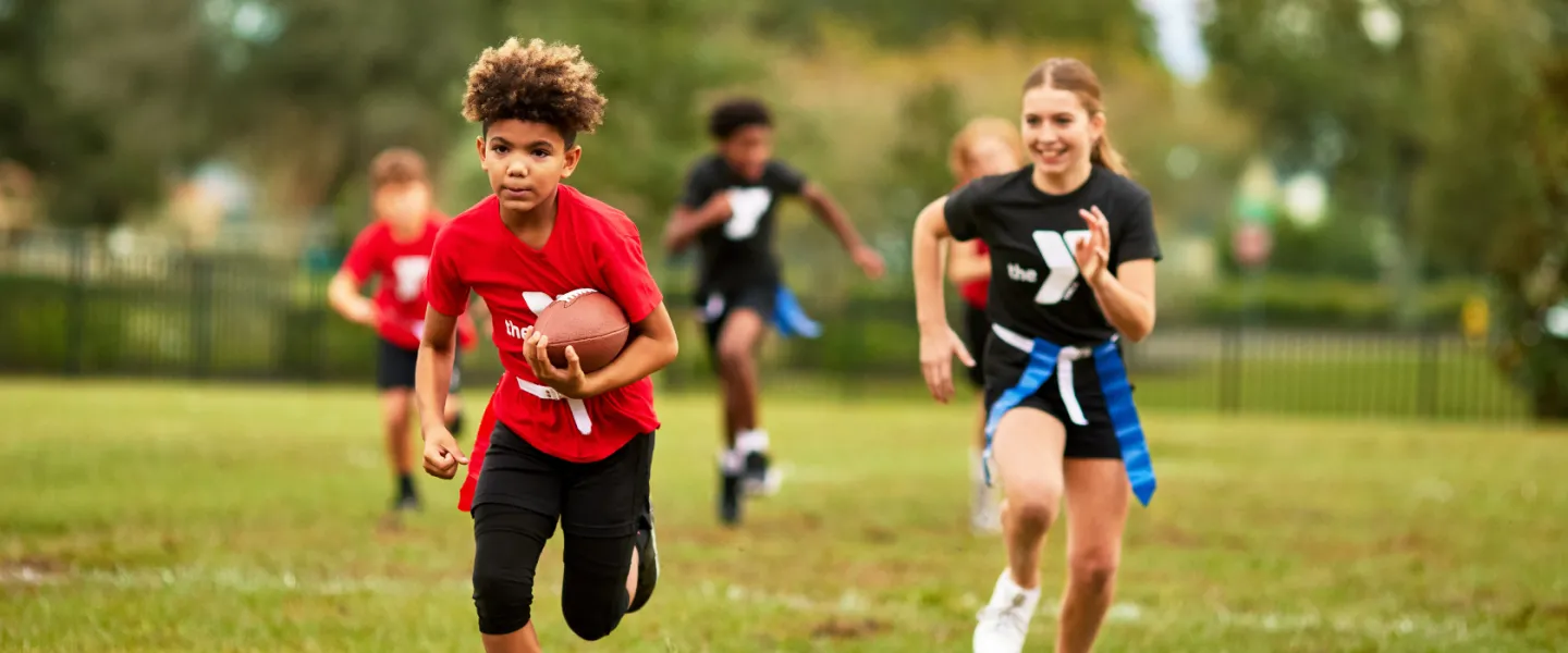 boy and girl running while playing flag football