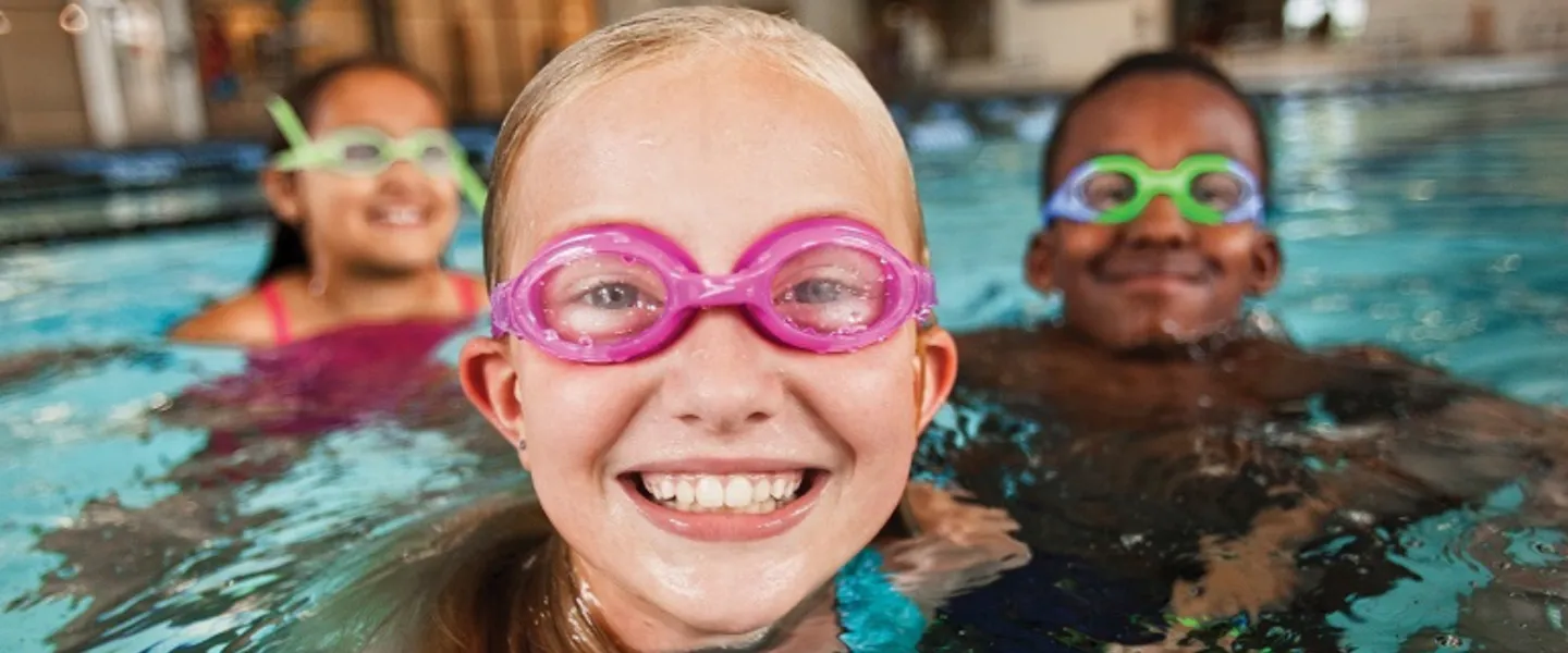 close up of three kids in the pool wearing goggles