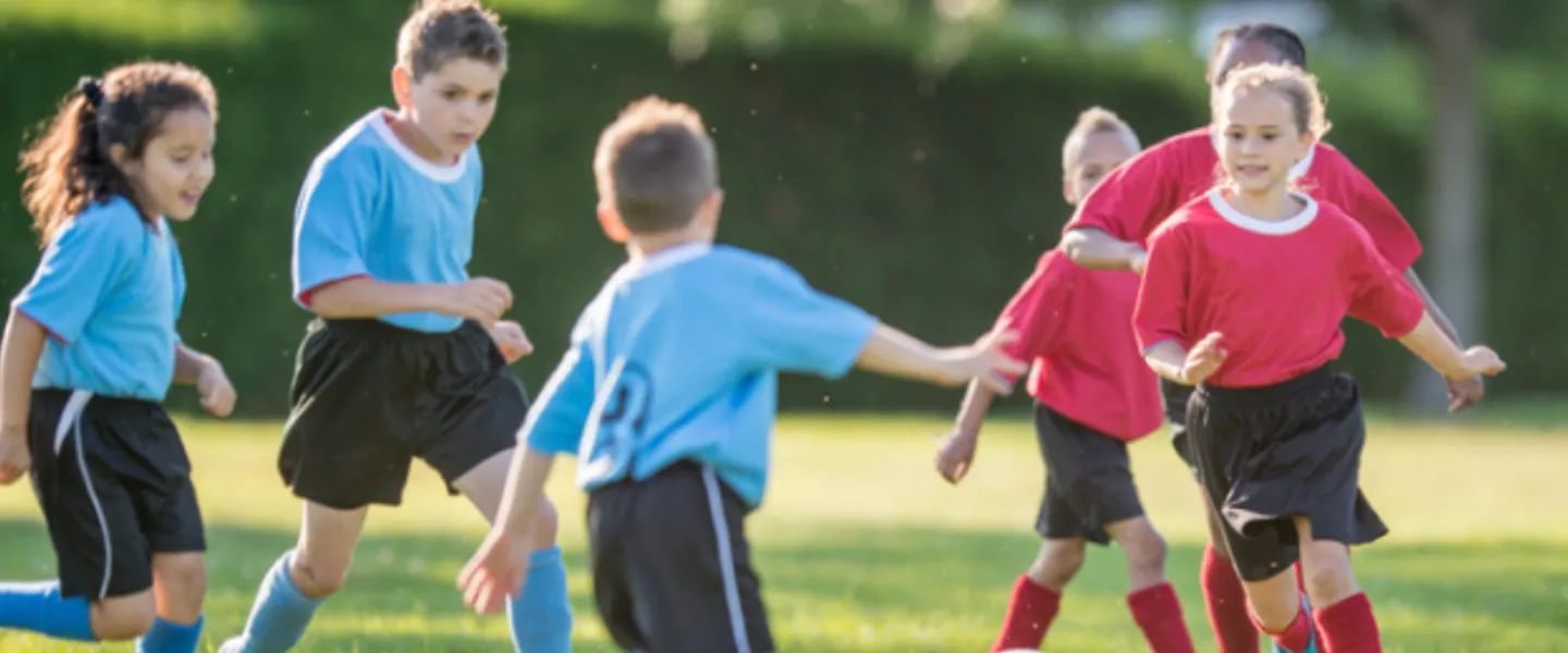 youth boys and girls playing a soccer game