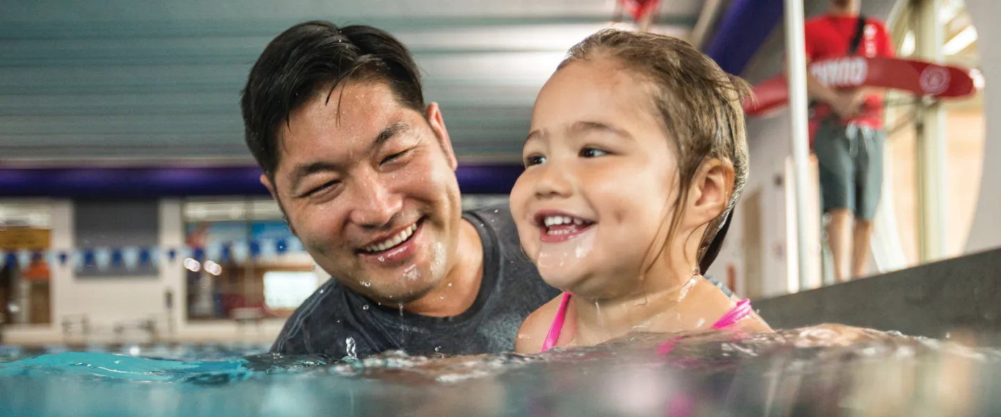 father teaching young daugther how to swim