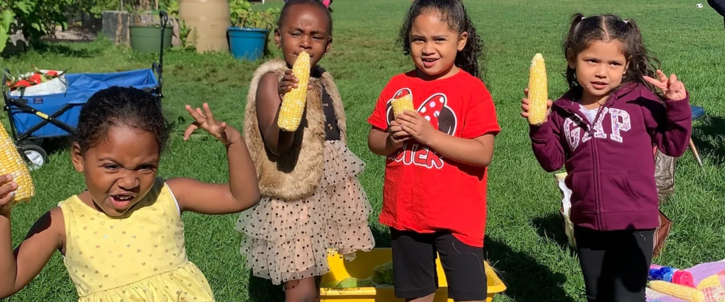 image of four little girls holding pieces of corn on the cob