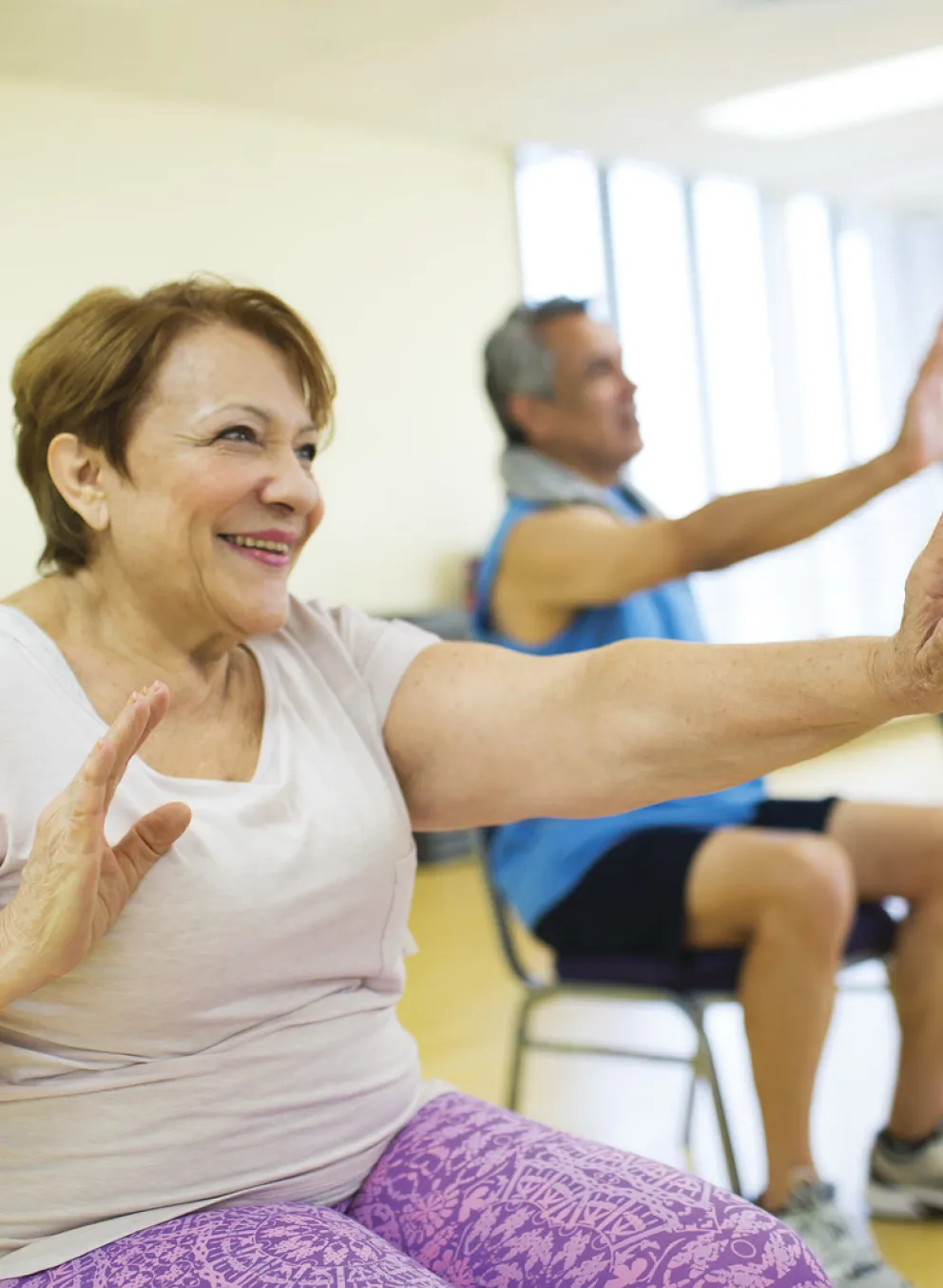 senior citizens smiling and exercising while seated