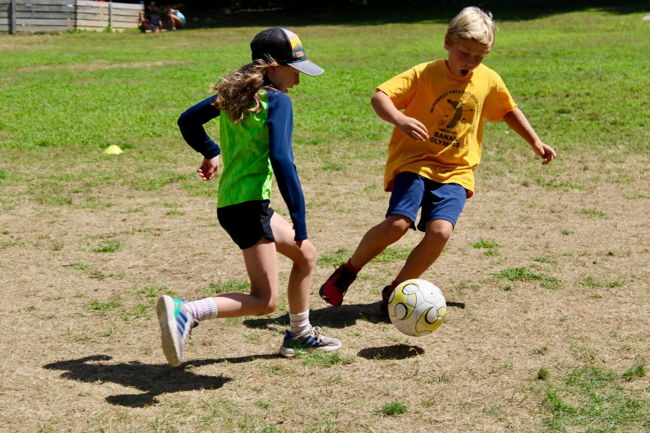 photo of two kids running after a soccer ball