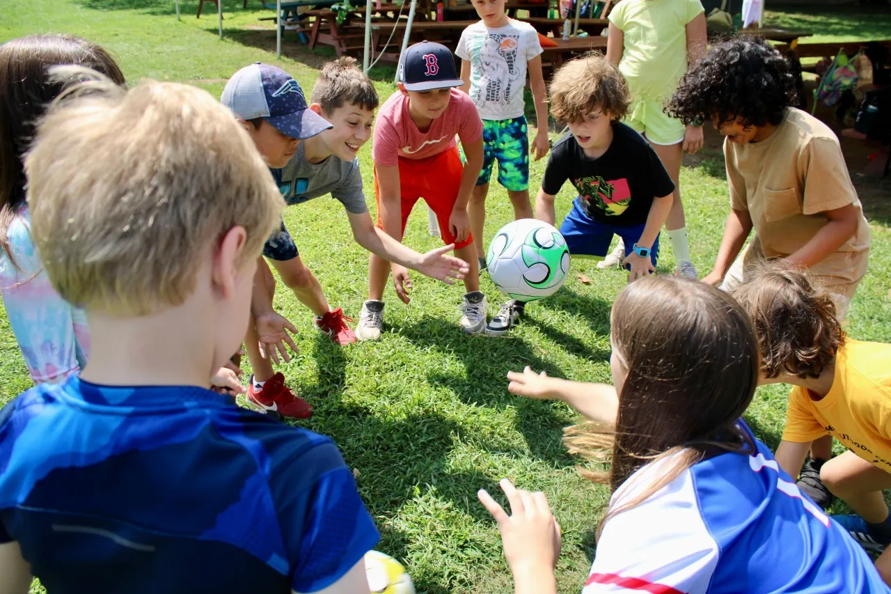 photo of a group of campers circled around a soccer ball