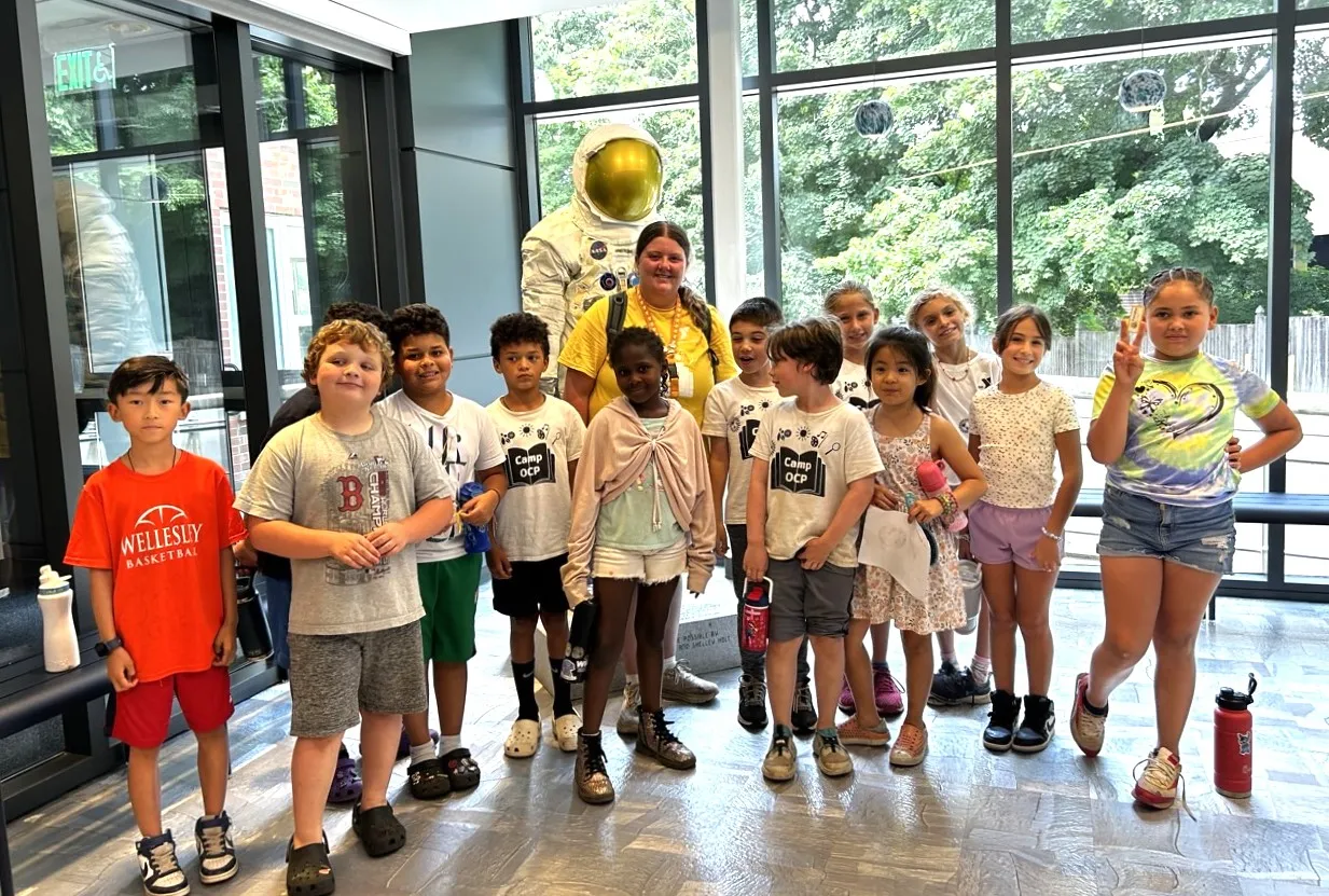 group photo of campers posing in front of an astronaut statue