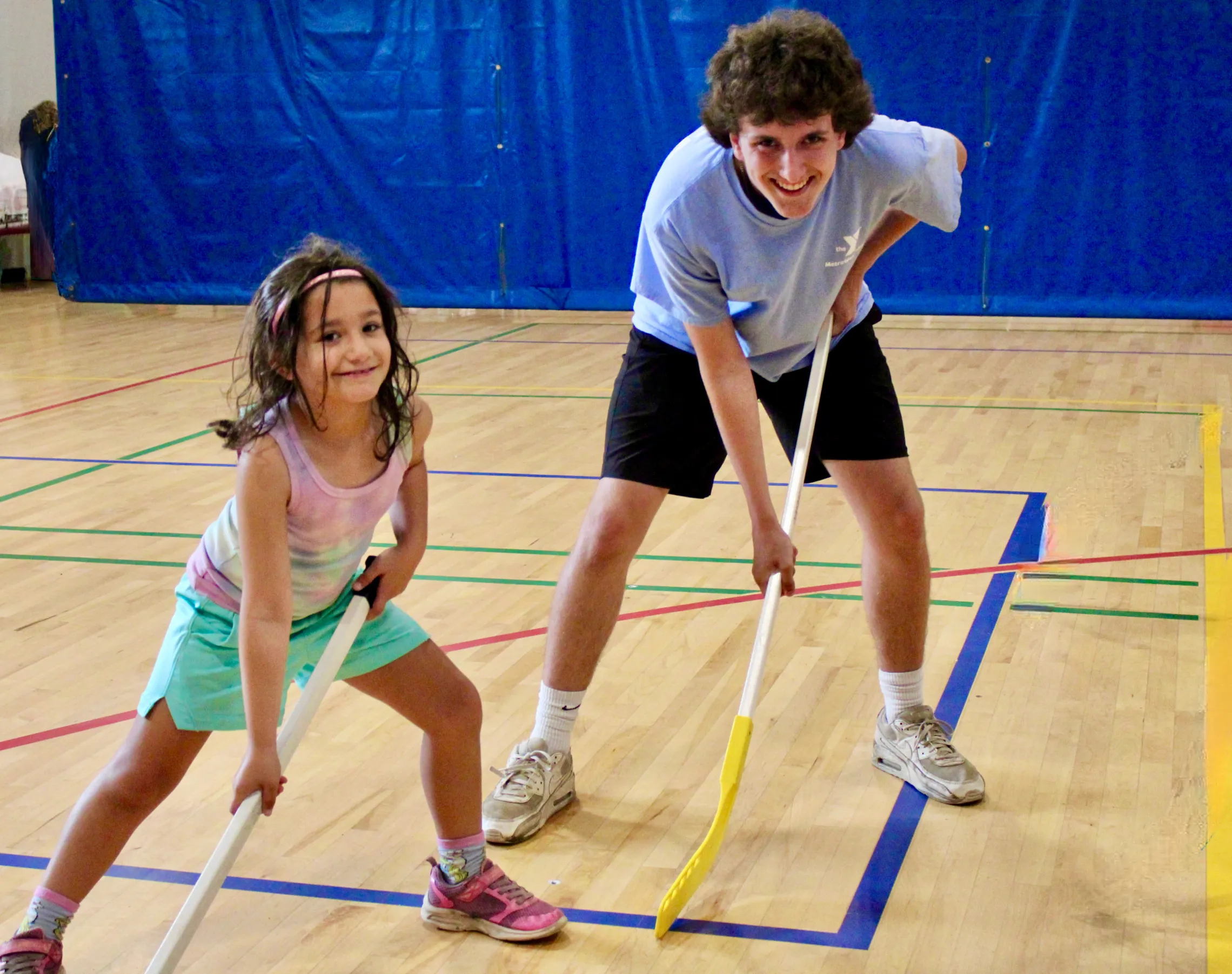 image of camper and camp counselor playing floor hockey