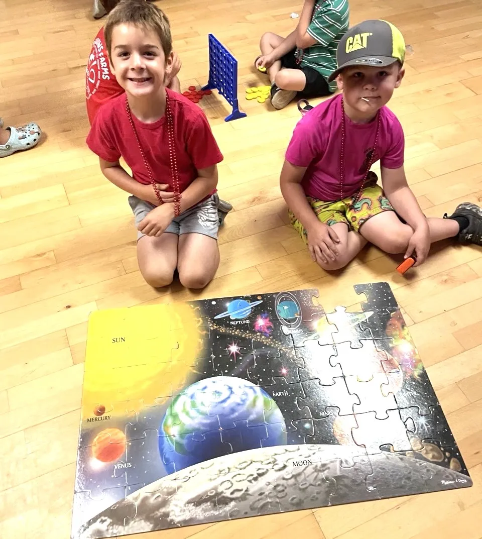 two boys showing completed outer space puzzle