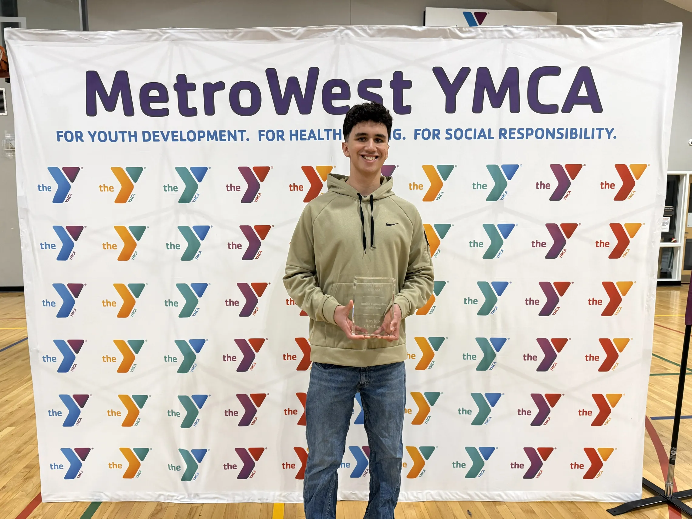 male camp counselor posing for photo holding an award