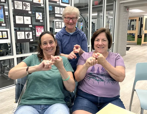 three women signing the word "friend" in American Sign Language