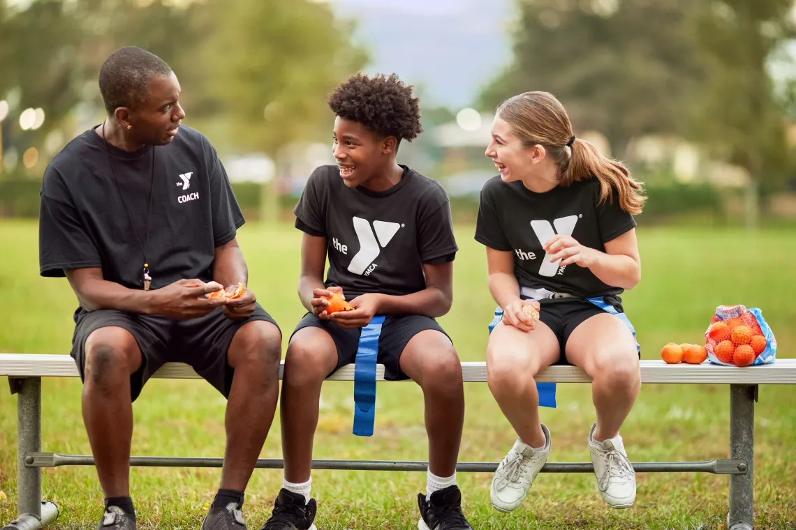 coach sitting with boy and girl flag football participants