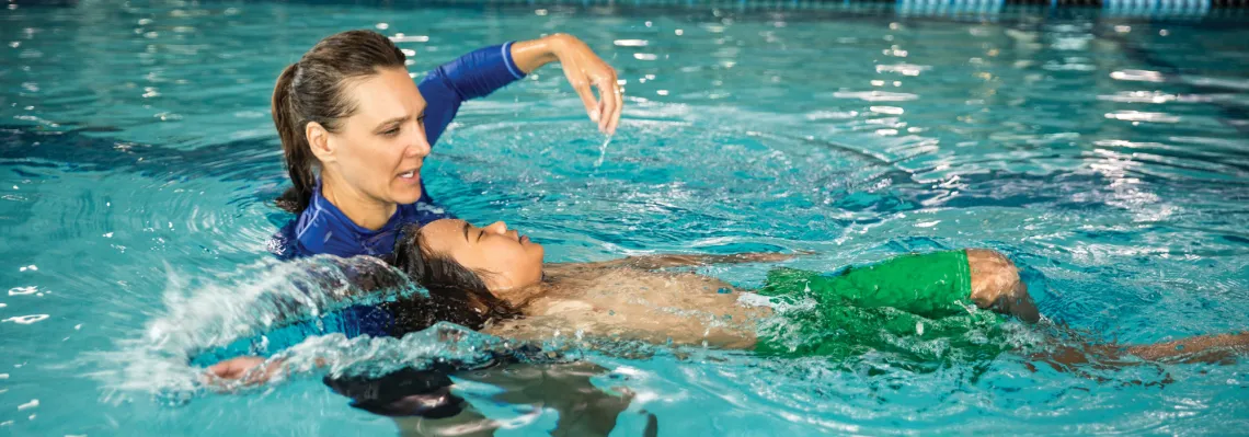 young boy doing the backstroke during swim lesson