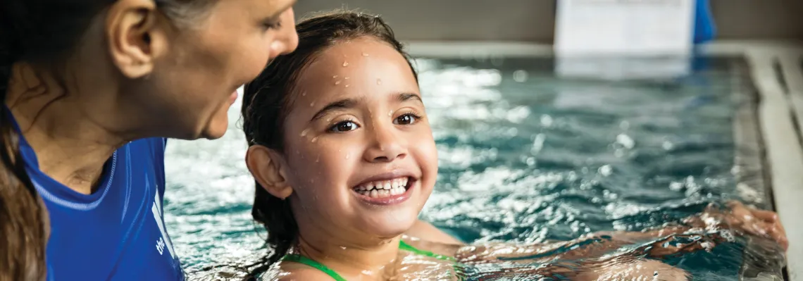 close up of a young girl in the pool with swim instructor