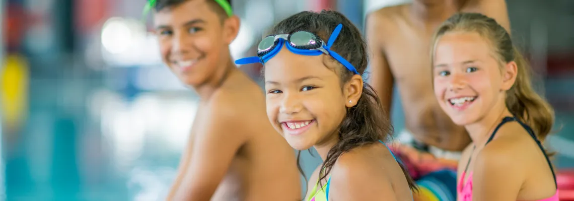 close up of three kids sitting on the edge of the pool