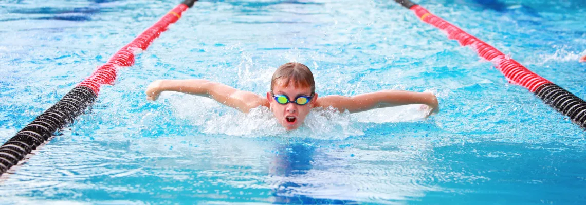 close up of young boy doing the butterfly stroke in the pool