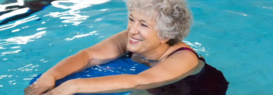 woman walking in the pool while leaning on a blue float