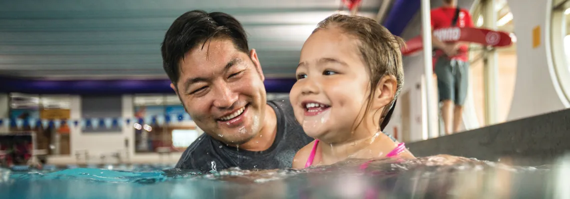 father teaching young daugther how to swim