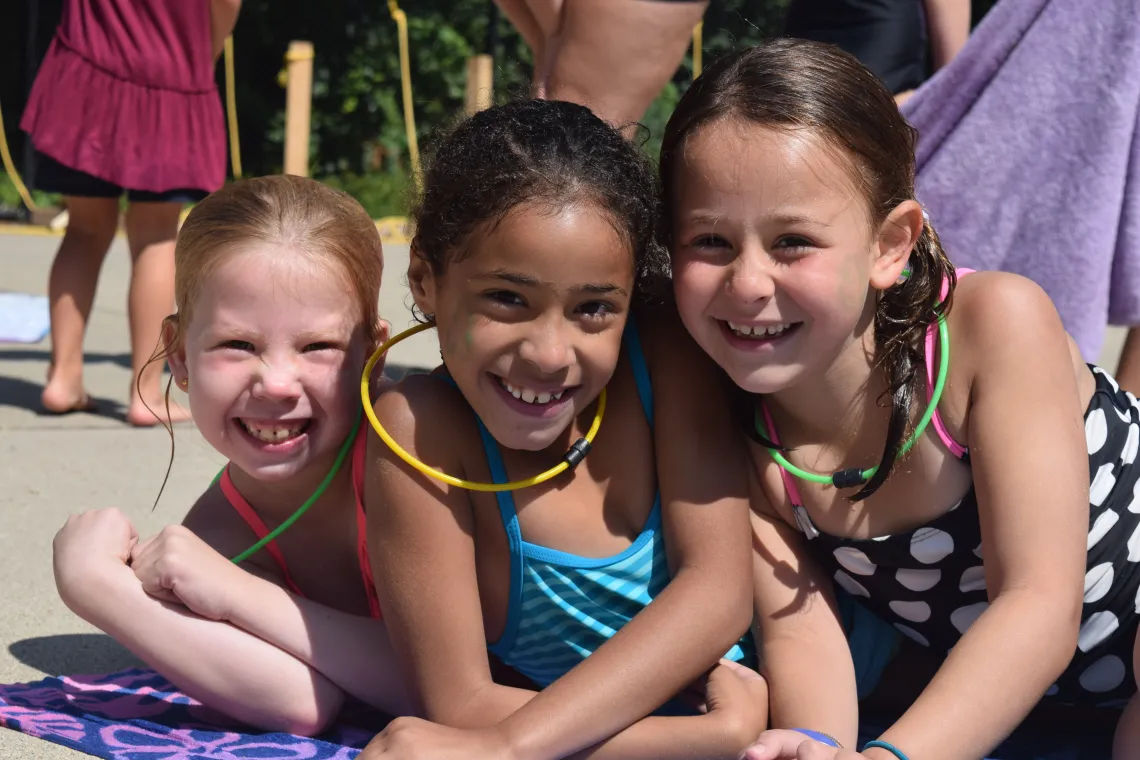 three girls smiling together at the pool