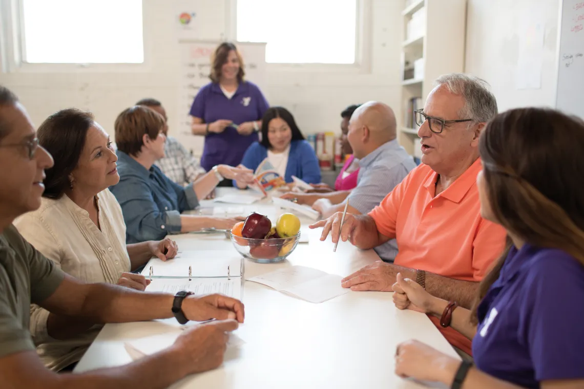 group of adults sitting around a table talking