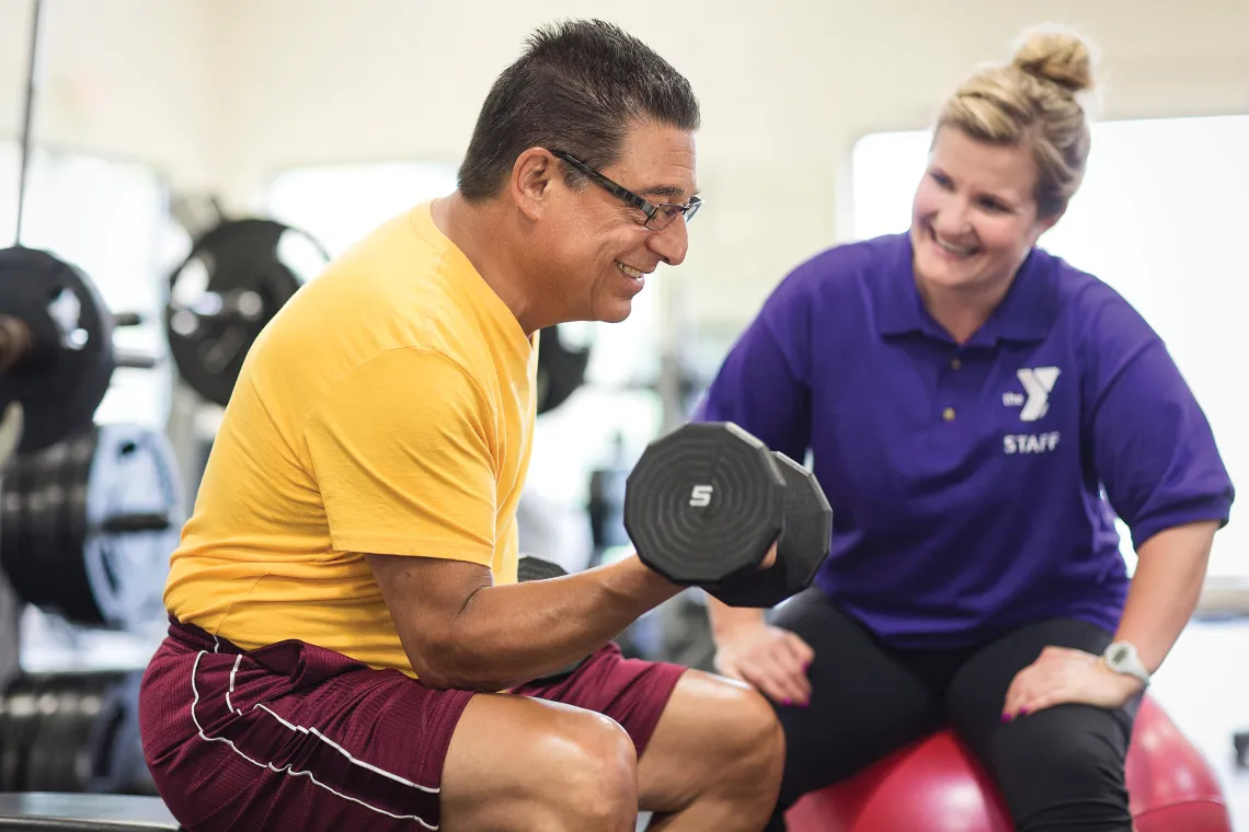 female y staff helping member with strength training