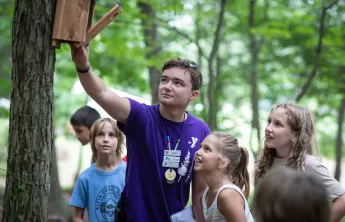 image of camp counselor showing campers a bird feeder
