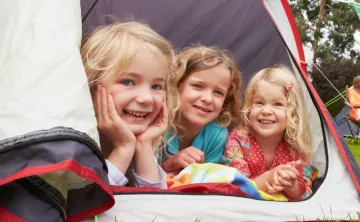 three young girls sitting together in a tent