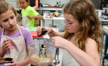 two girls measuring ingredients in cooking class