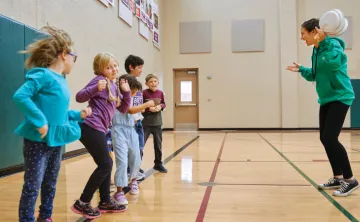 staff member and group of kids in gymnasium