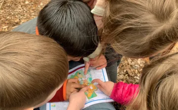 image of young kids huddled around a map